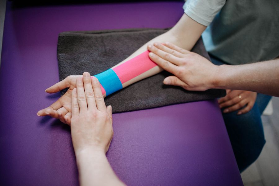 Therapist applying kinesio tape treatment for cubital tunnel syndrome