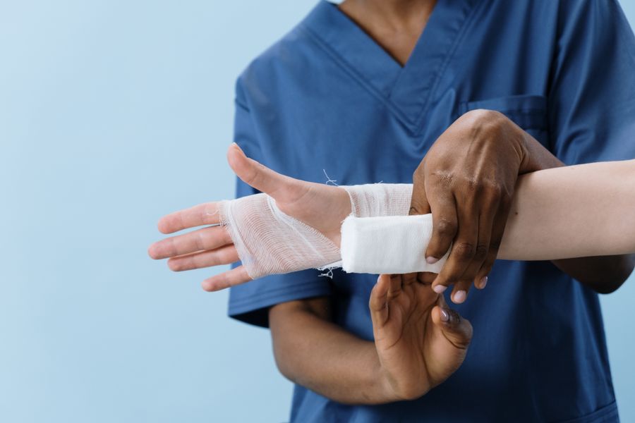 Healthcare professional carefully wrapping a patient's injured hand with gauze after a fracture