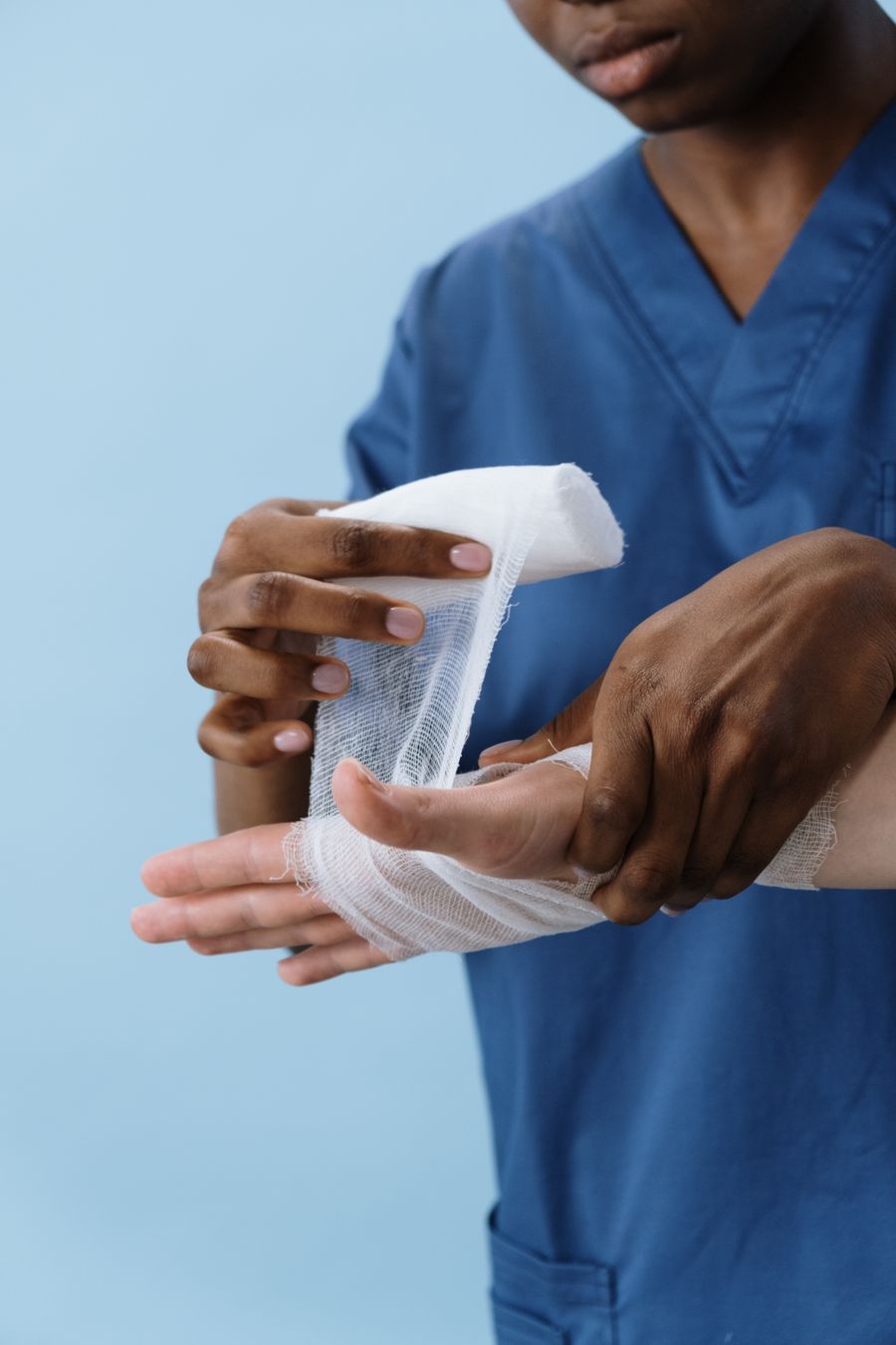Healthcare professional wrapping a patient's hand with gauze dressing following hand surgery