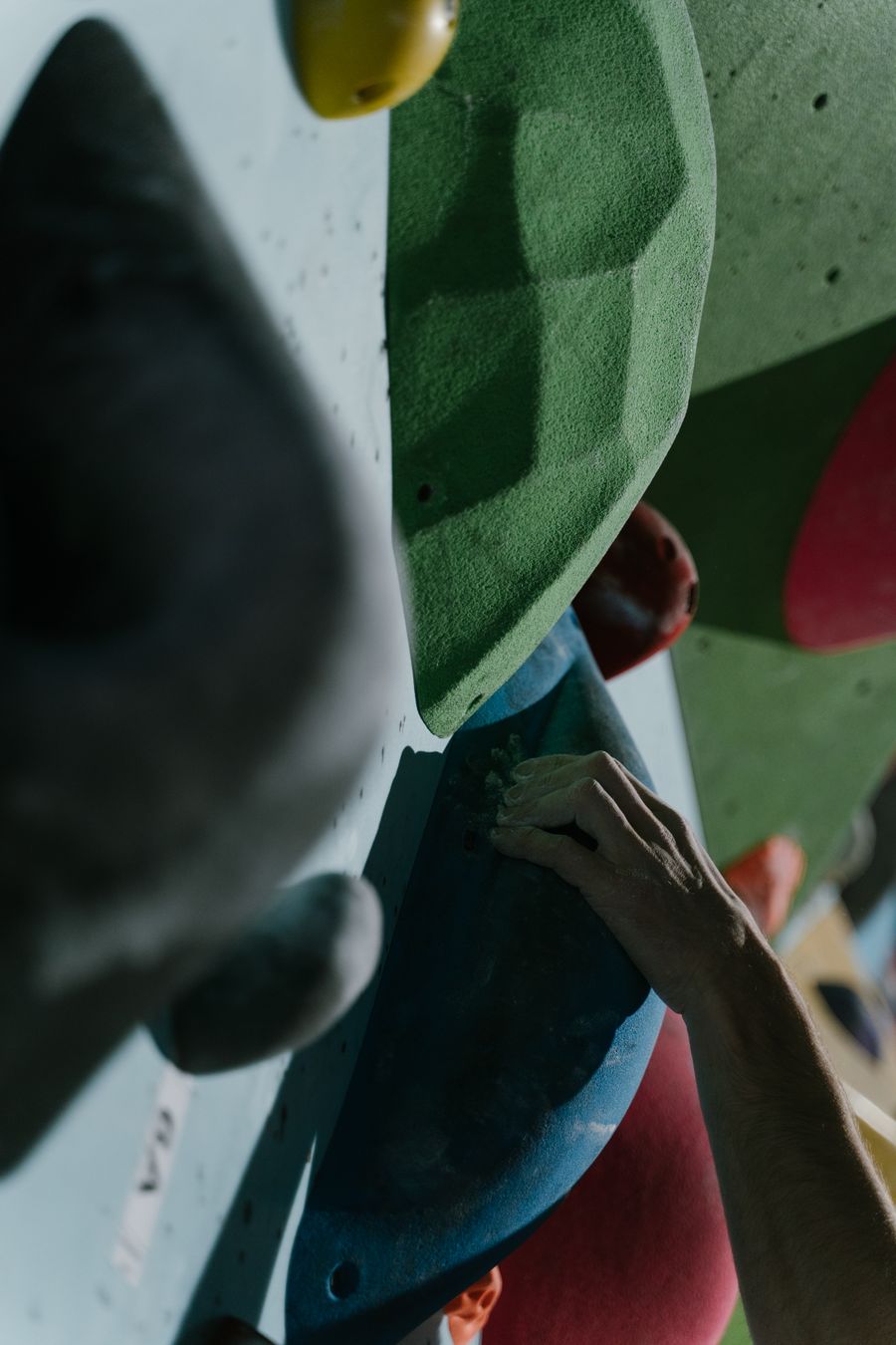 Climber's hand gripping an indoor climbing hold — the type of load that can cause finger tendon injuries