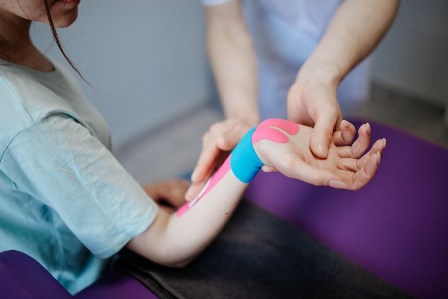Therapist applying kinesio tape to a patient's wrist for TFCC tear treatment